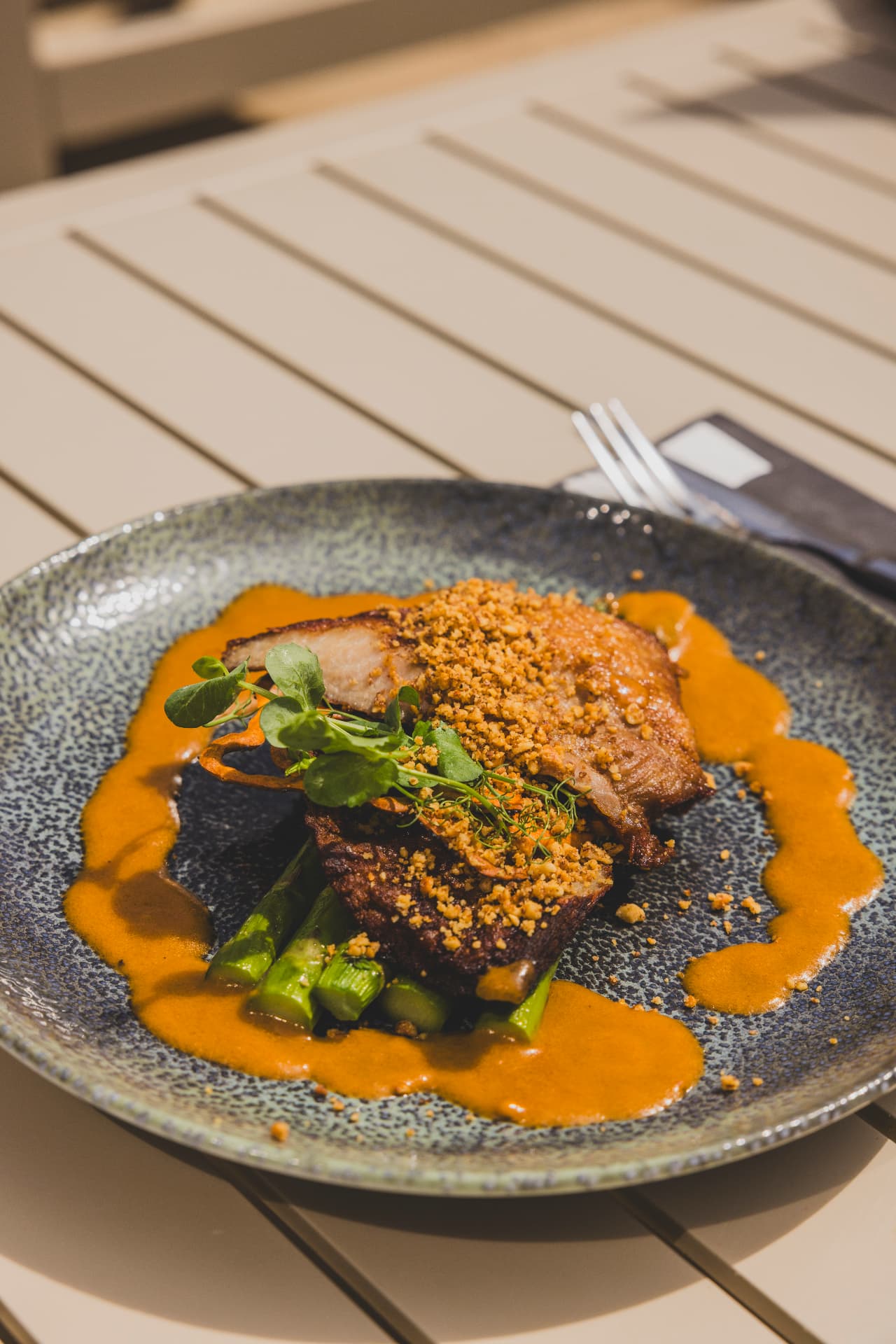 Buikspek met groene asperges en een romige saus
