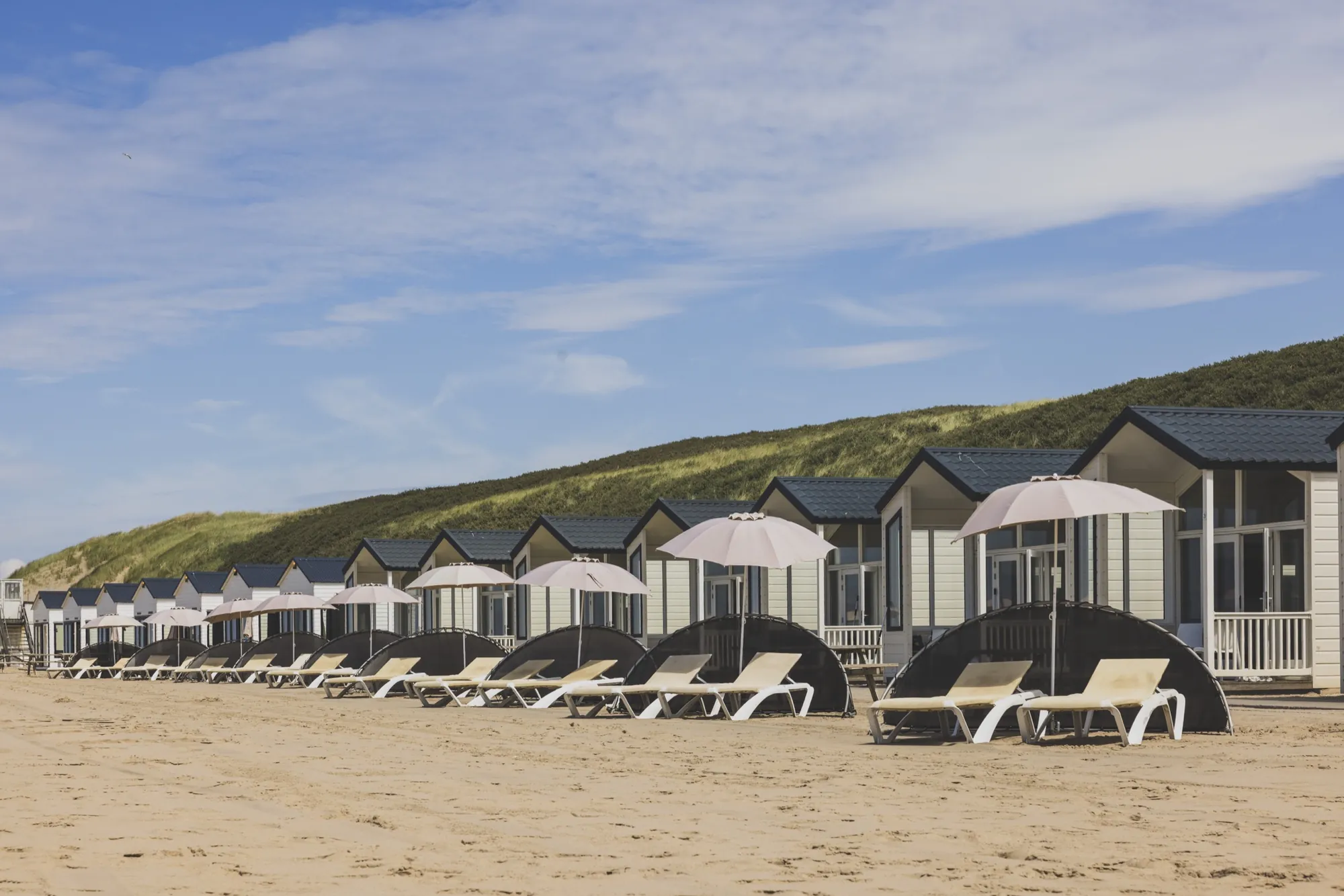 Strandbungalows met parasols en ligbedden voor de deur